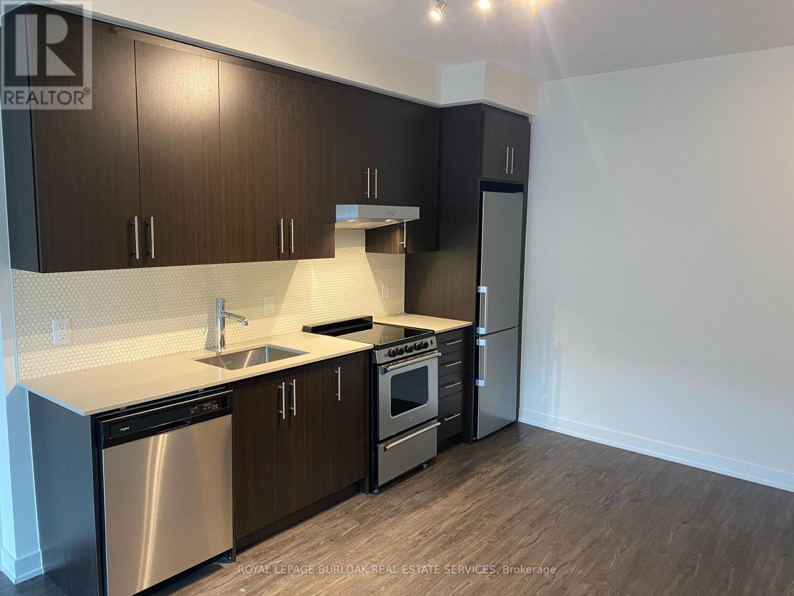 A kitchen with dark wood cabinets and stainless steel appliances.