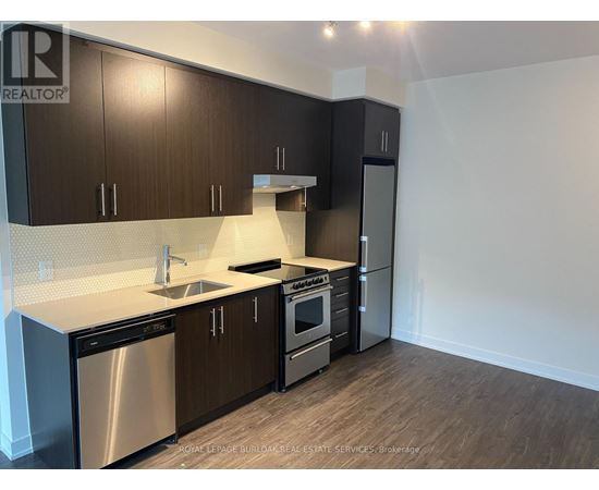 A kitchen with dark wood cabinets and stainless steel appliances.