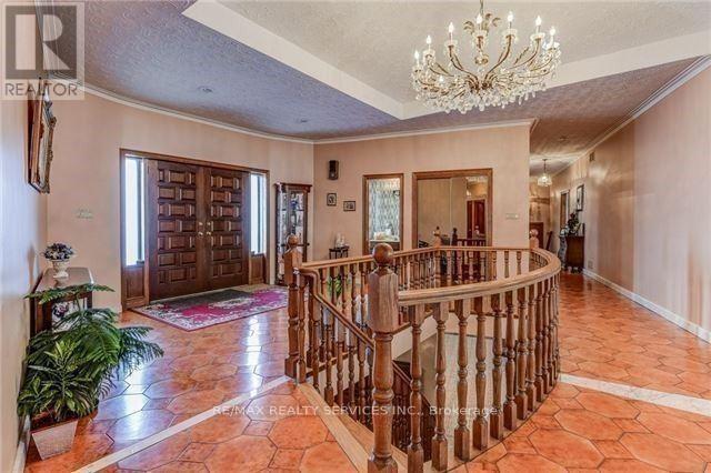 A large foyer with a chandelier, a staircase, and a plant.
