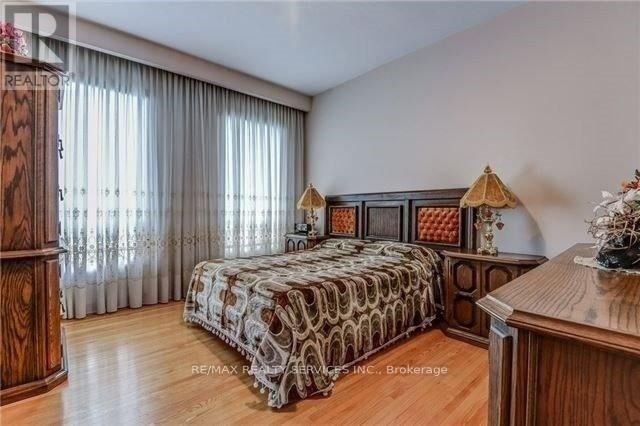 A bedroom with a patterned bedspread and a wooden dresser.