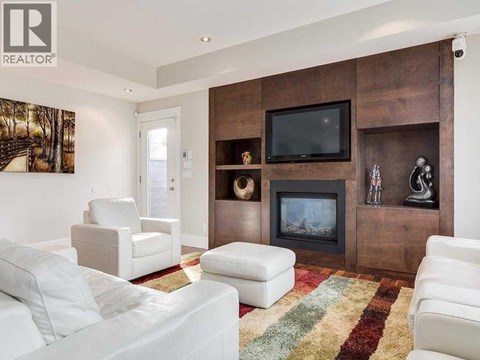 A living room with a fireplace and a television on the wall.