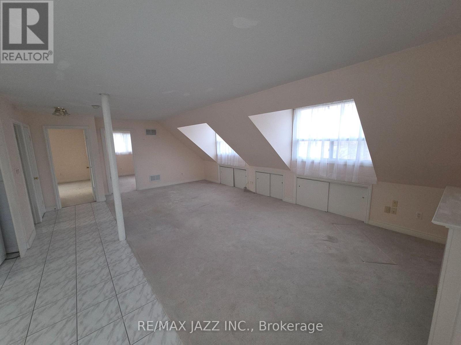 A large empty room with a tiled floor and skylights.