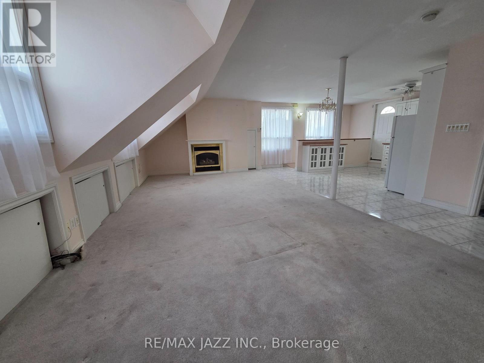 A spacious room with a staircase on the left and a kitchen area on the right.