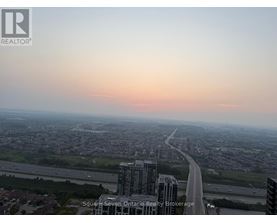 A cityscape with a highway and buildings under a pink sky.