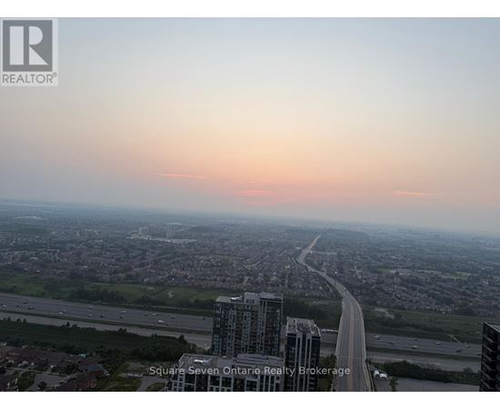 A cityscape with a highway and buildings under a pink sky.
