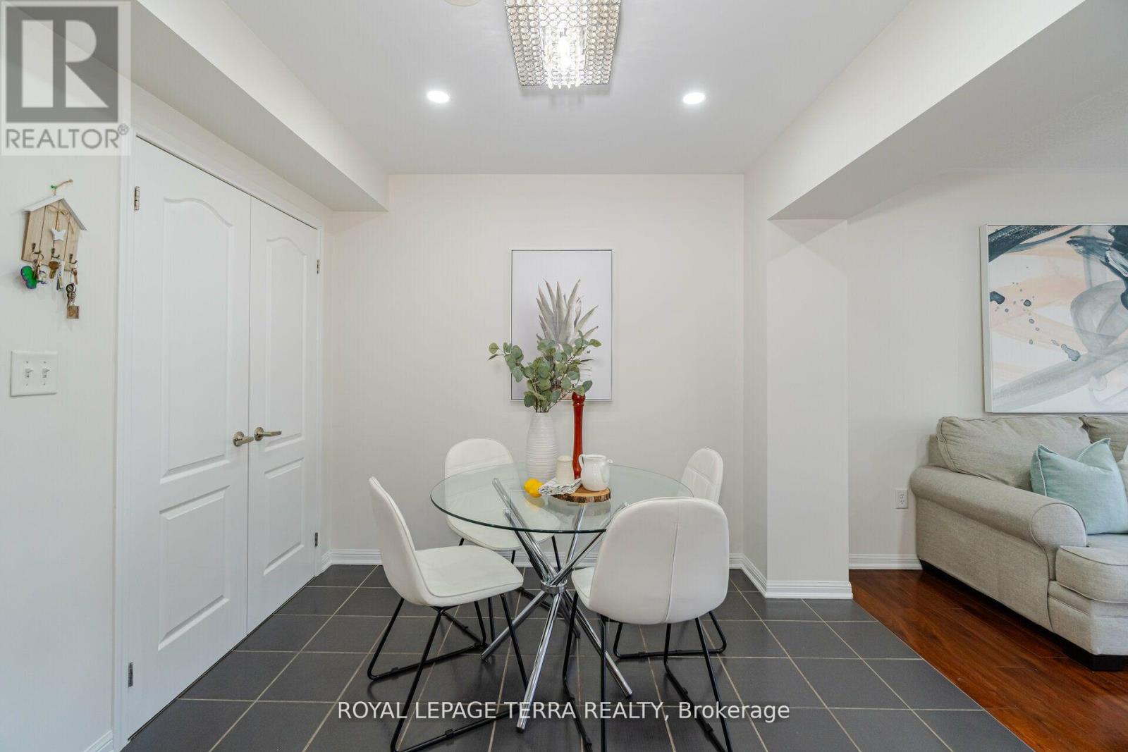 A dining room with a glass table and white chairs.