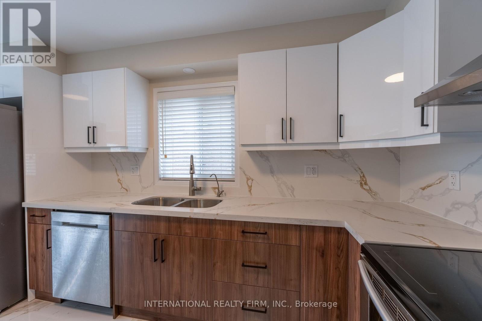 A kitchen with white cabinets and a marble countertop.