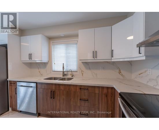 A kitchen with white cabinets and a marble countertop.