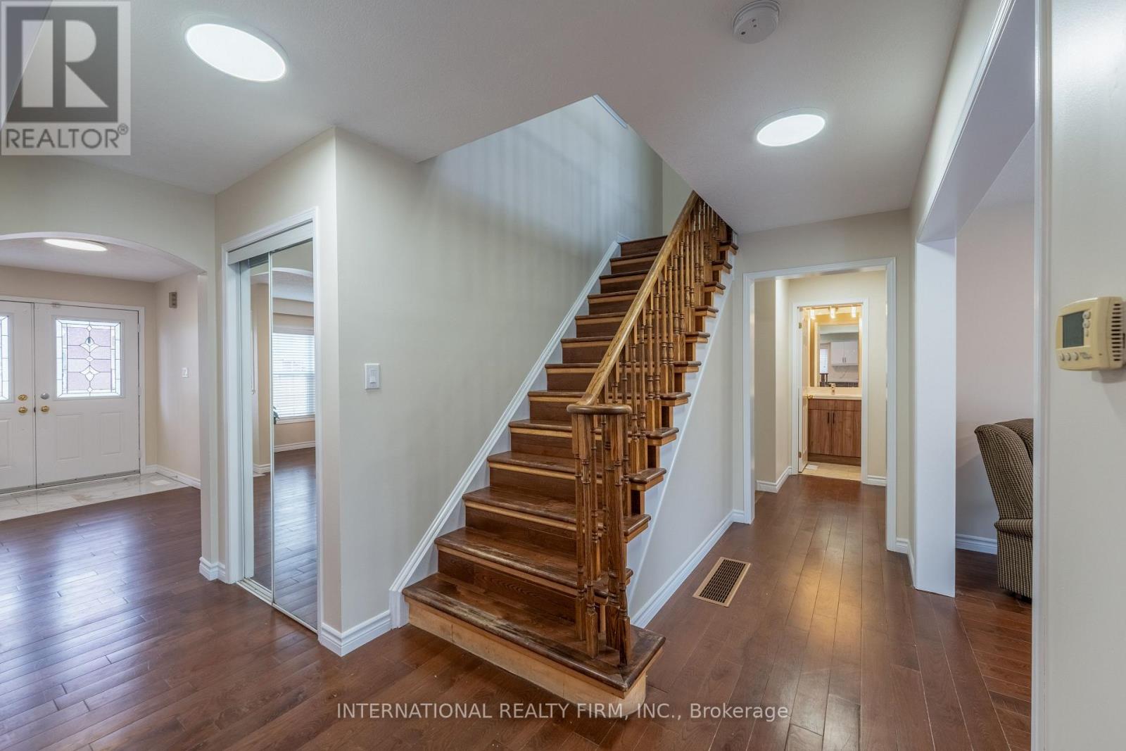 A spacious hallway with a wooden staircase and a chair.