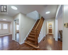 A spacious hallway with a wooden staircase and a chair.