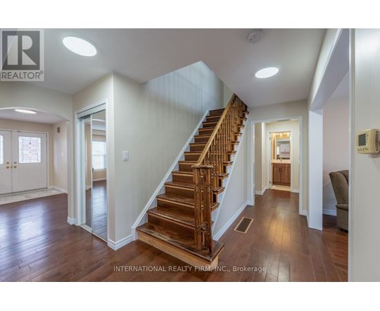 A spacious hallway with a wooden staircase and a chair.