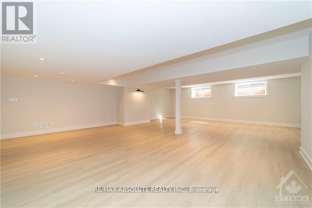 A spacious room with wooden flooring and white walls.