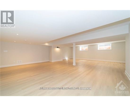 A spacious room with wooden flooring and white walls.