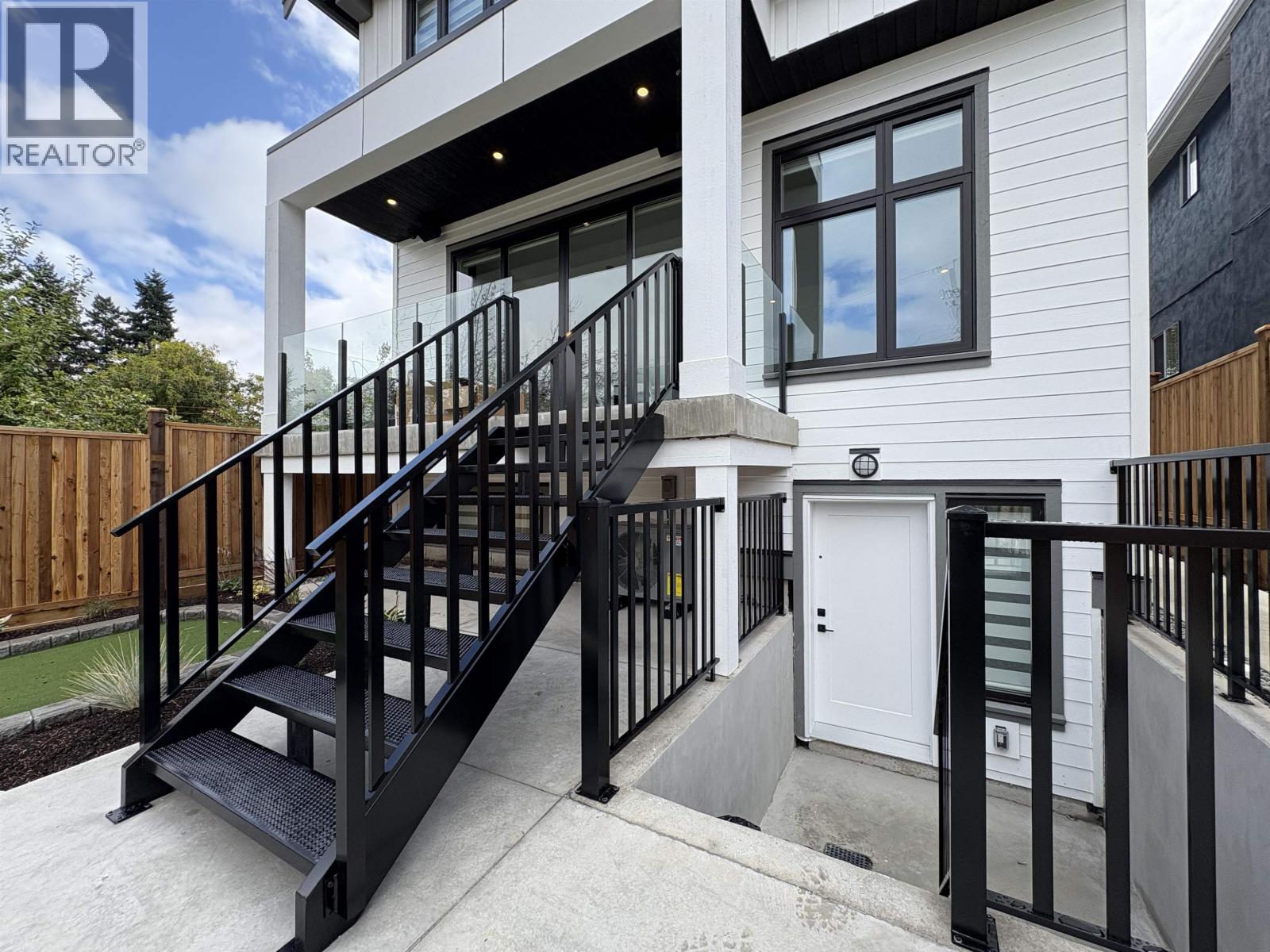 A modern house with a white exterior and a black metal staircase.