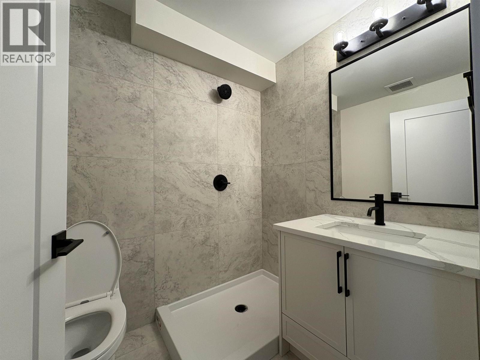 A bathroom with a toilet, sink, and mirror.