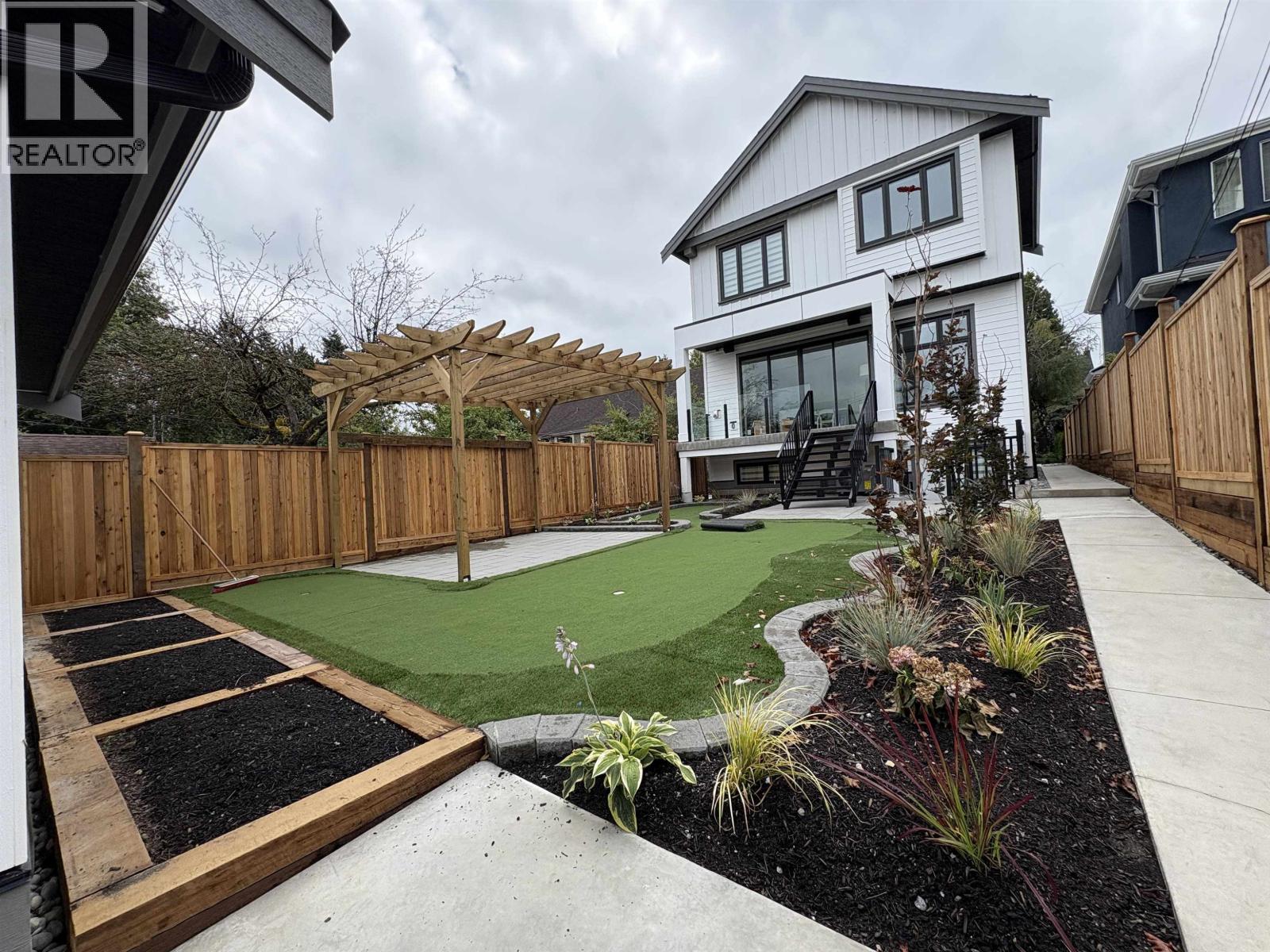 A white house with a green lawn and a wooden fence.