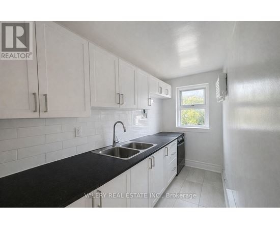 A kitchen with white cabinets and black countertops.
