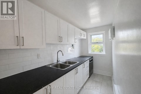 A kitchen with white cabinets and black countertops.
