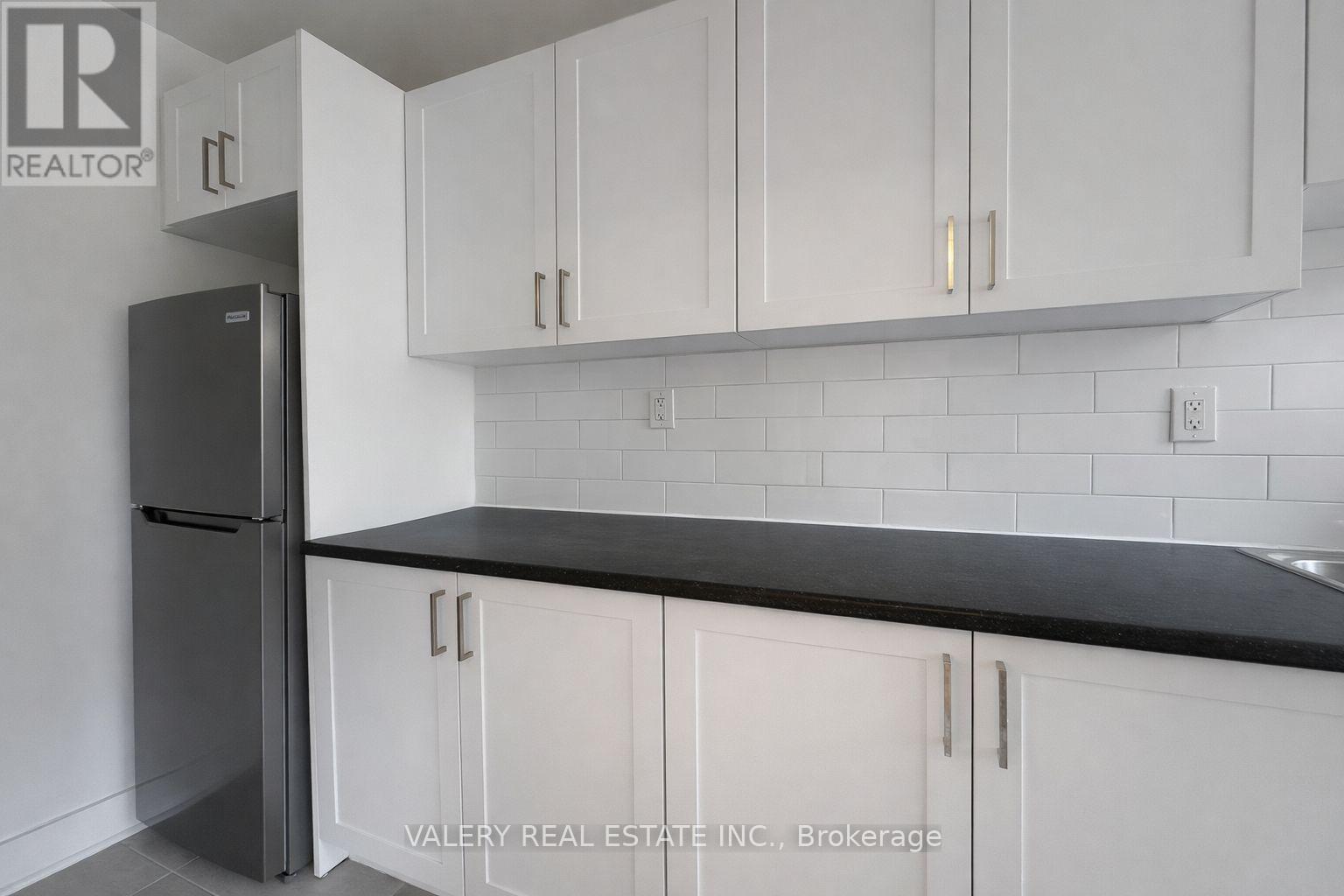 A kitchen with white cabinets and a black countertop.