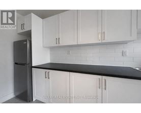 A kitchen with white cabinets and a black countertop.