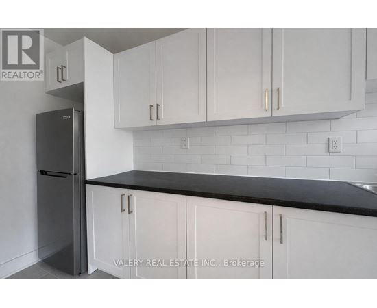 A kitchen with white cabinets and a black countertop.