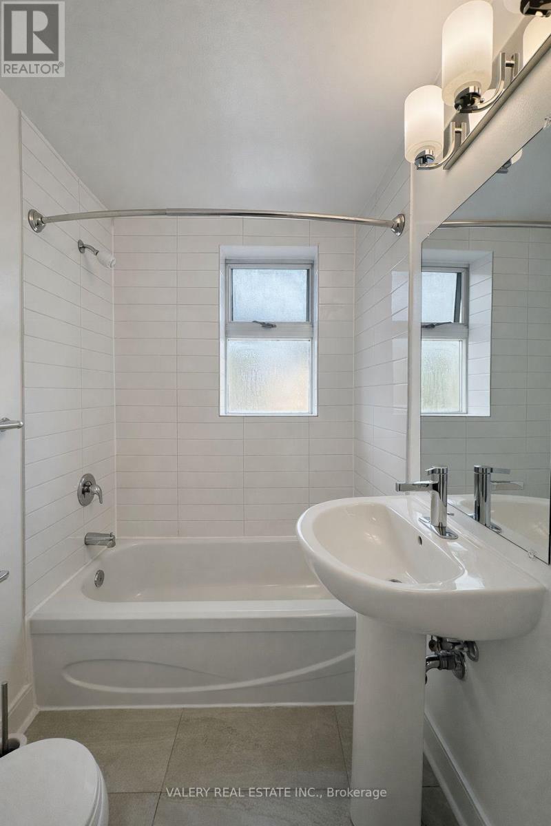 A white bathroom with a tub, sink, and toilet.