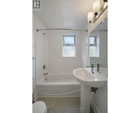 A white bathroom with a tub, sink, and toilet.