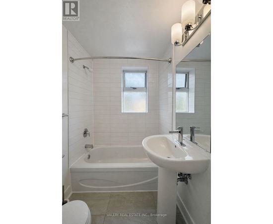 A white bathroom with a tub, sink, and toilet.