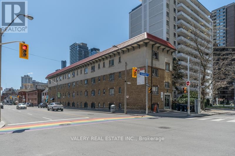 A street view of a building with a rainbow painted on the road.