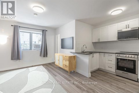 A kitchen with a wooden table and a flat screen TV mounted on the wall.