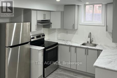 A kitchen with a refrigerator, oven, and sink.