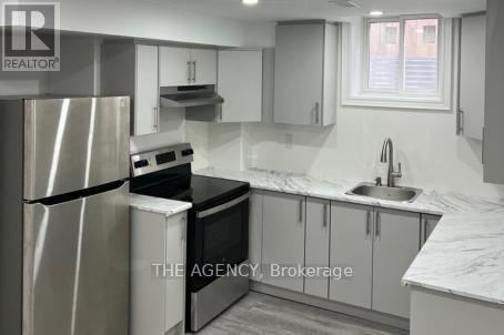 A kitchen with a refrigerator, oven, and sink.