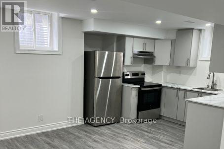 A kitchen with a refrigerator, oven, and cabinets.