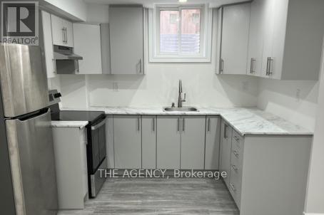 A kitchen with white cabinets and a stainless steel refrigerator.