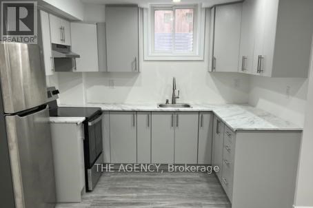 A kitchen with white cabinets and a stainless steel refrigerator.