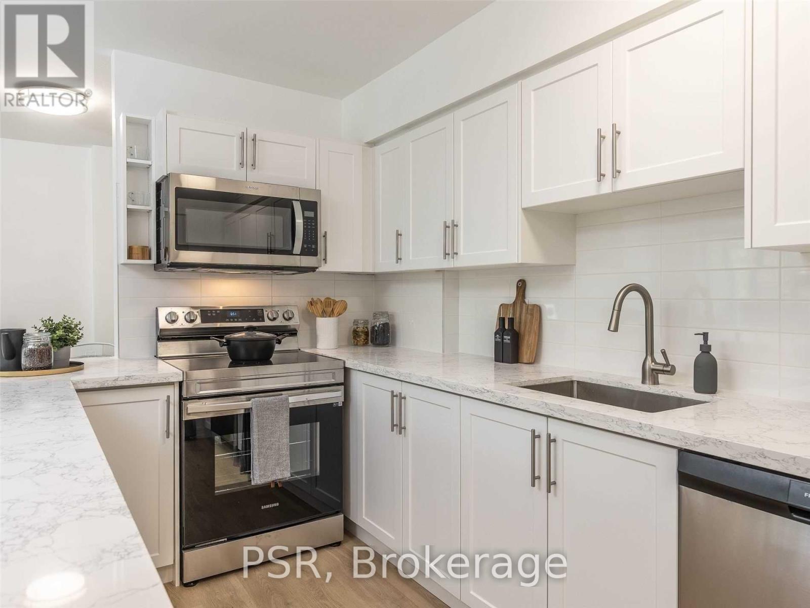 A kitchen with white cabinets and a marble countertop.