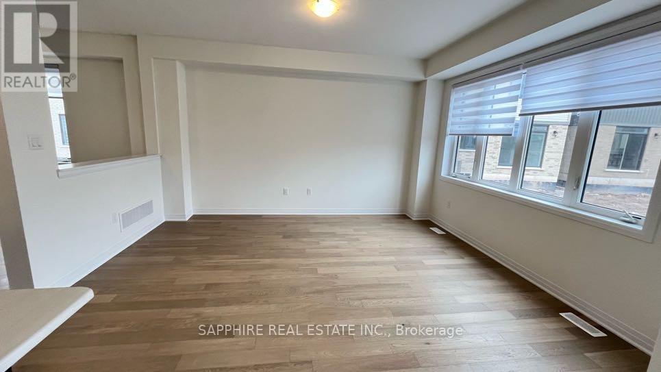 A room with wooden flooring and a window showing a view of other buildings.