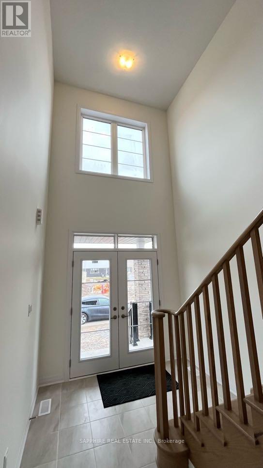 A hallway with a wooden staircase and a glass door leading to a balcony.