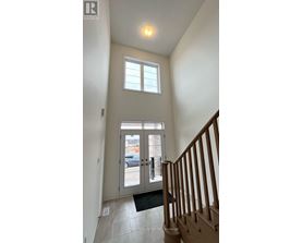 A hallway with a wooden staircase and a glass door leading to a balcony.
