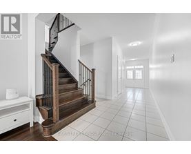 A spacious hallway with a staircase and a white console table.