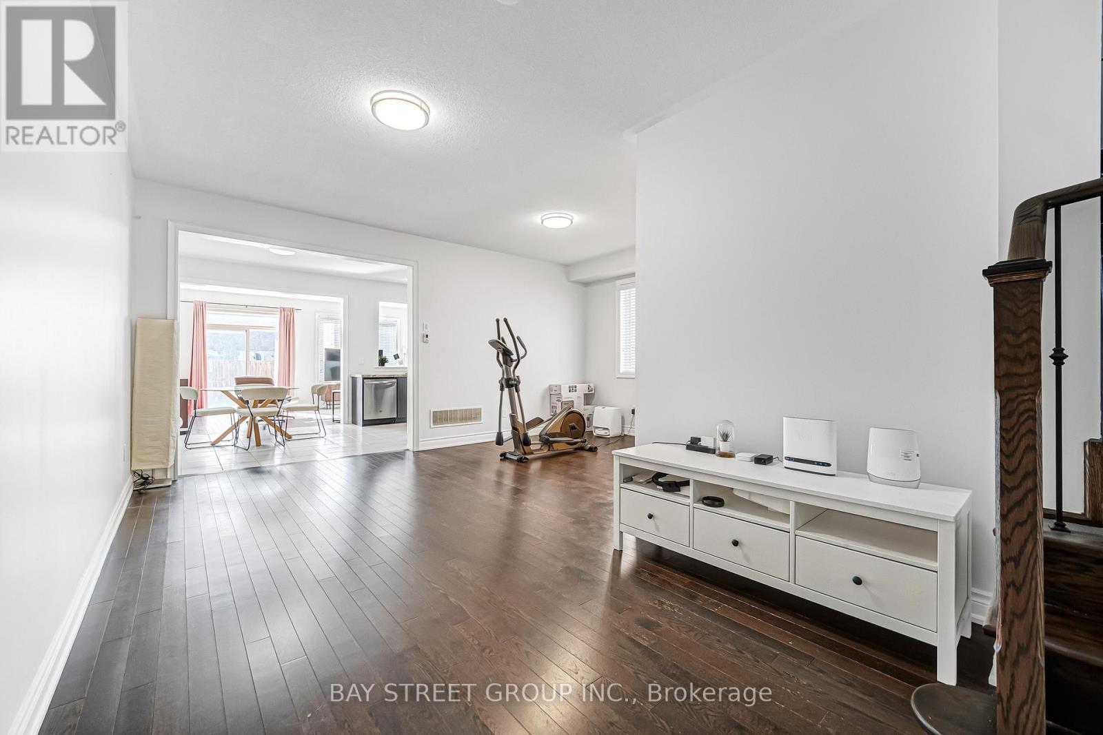 A spacious living room with a white sofa set and wooden flooring.