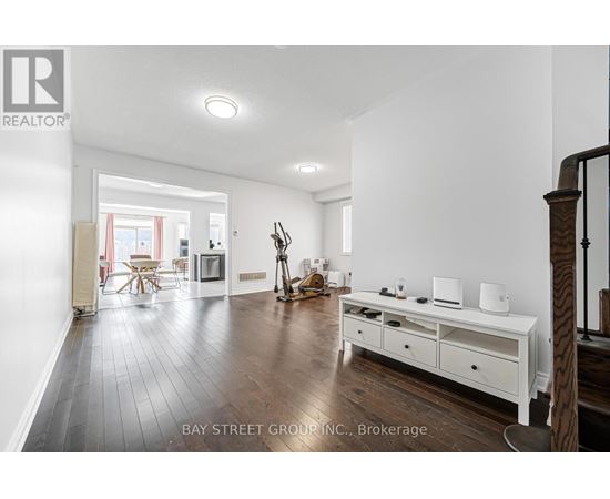 A spacious living room with a white sofa set and wooden flooring.