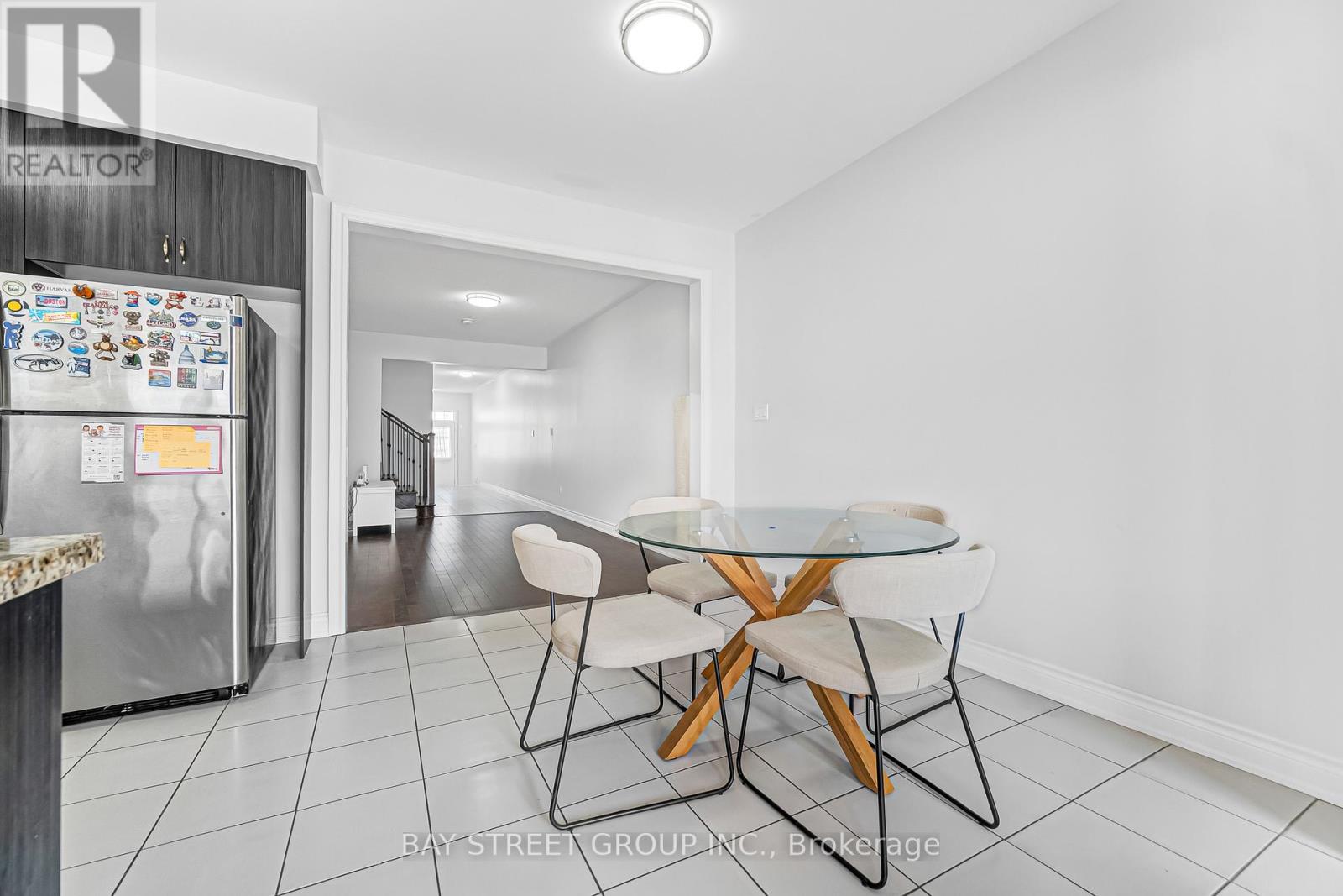 A kitchen with a refrigerator, table and chairs.