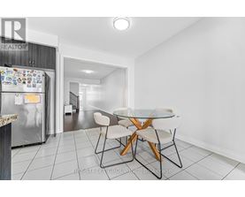 A kitchen with a refrigerator, table and chairs.