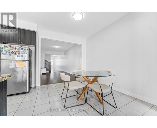 A kitchen with a refrigerator, table and chairs.