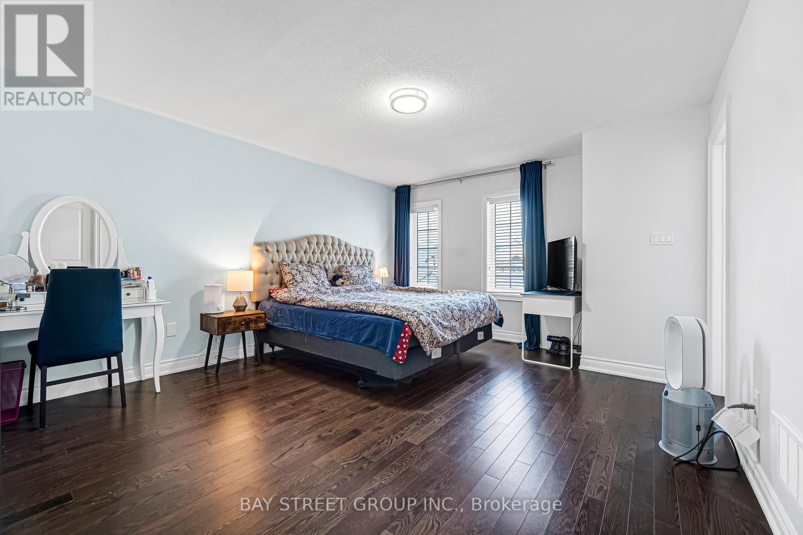 A bedroom with a bed, desk, chair, and window.