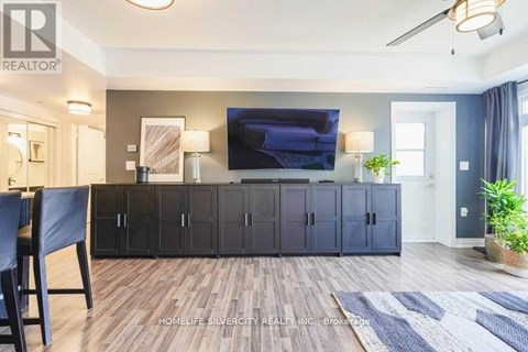 A living room with a tv on the wall and a cabinet with a mirror.