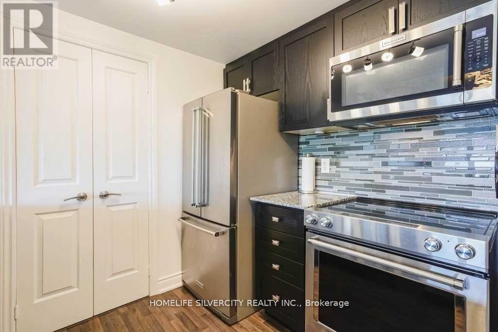 A kitchen with a refrigerator, microwave, oven and cabinets.