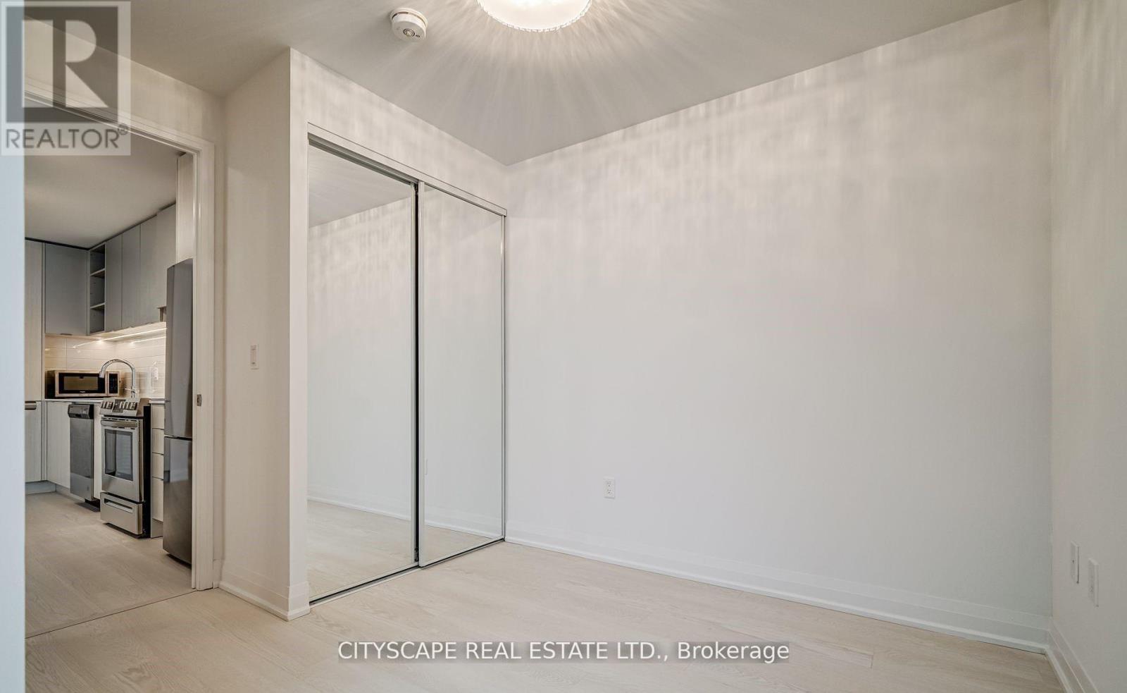 A real estate listing photo of a white bedroom with a sliding door.