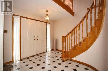 A hallway with a checkered floor and a wooden staircase.
